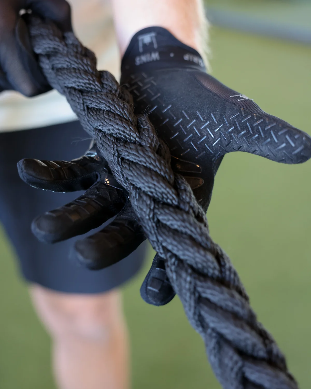 The gloved palm closed around a battle rope, silicone tread along the fingers