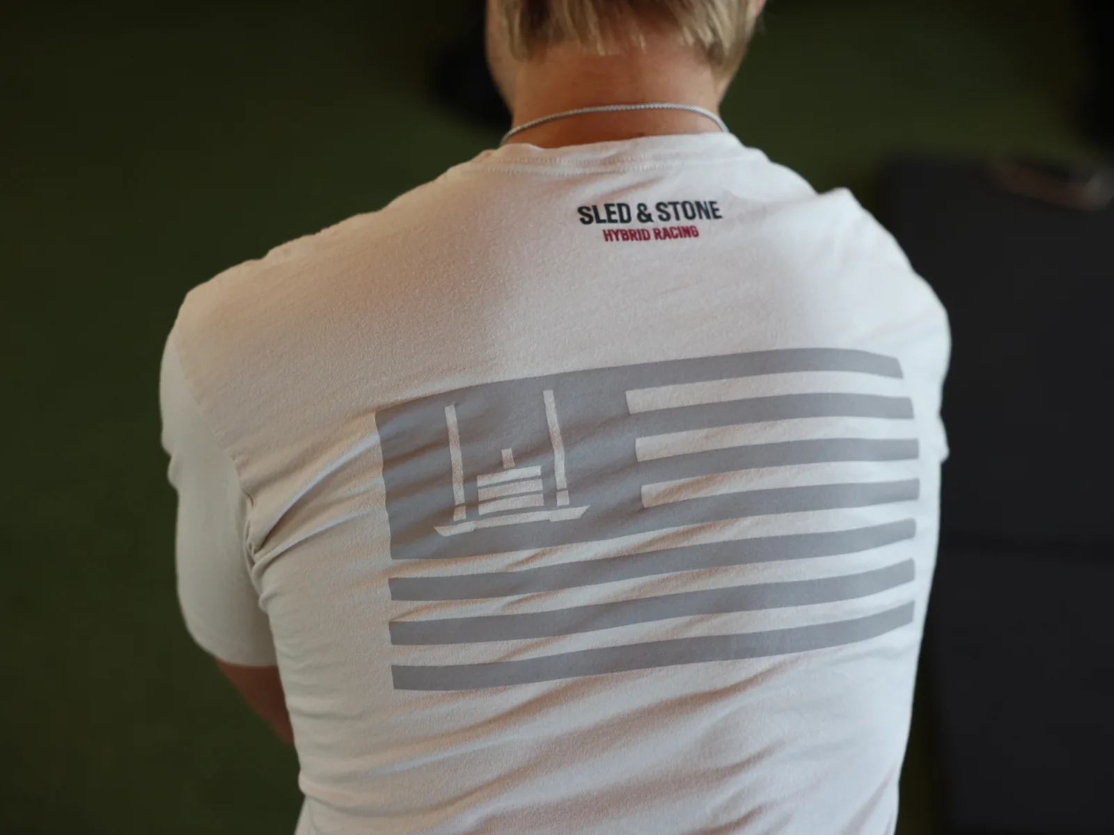 The Grip Wins Races tee in black and sand, worn side by side: Sled & Stone across the chest over Grip Wins Races — view 3