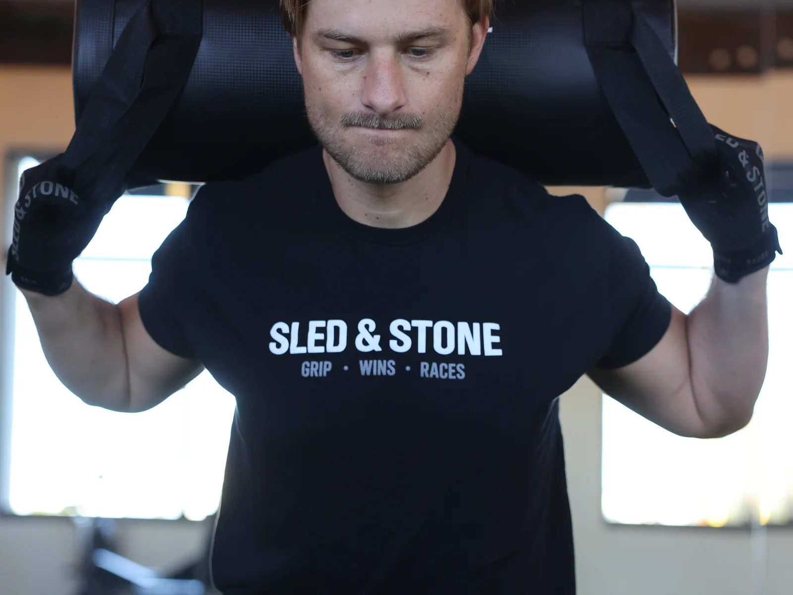 The Grip Wins Races tee in black and sand, worn side by side: Sled & Stone across the chest over Grip Wins Races — view 4