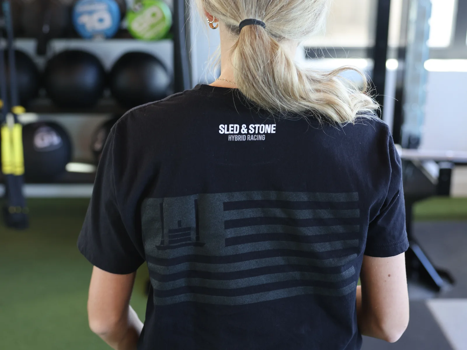 The Grip Wins Races tee in black and sand, worn side by side: Sled & Stone across the chest over Grip Wins Races — view 2